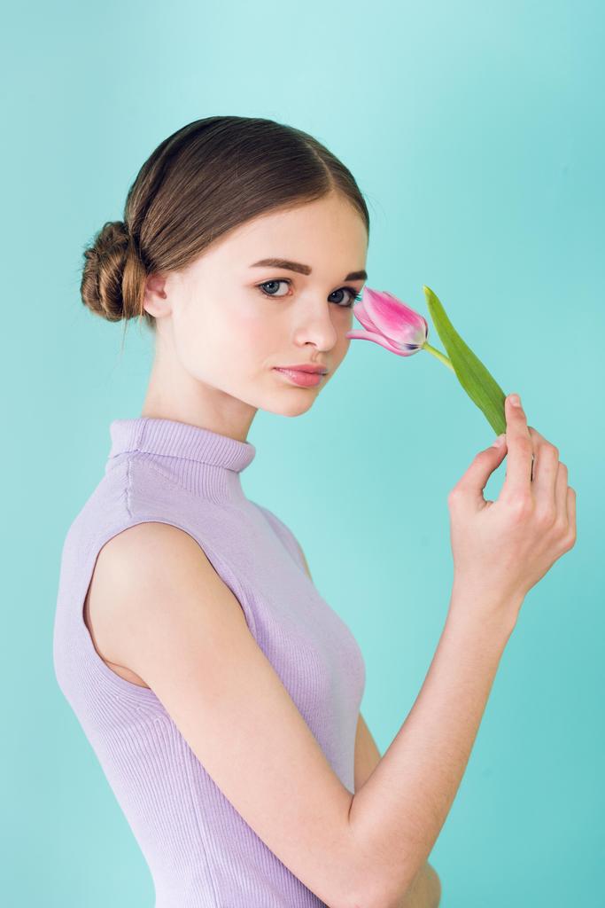 szép tini lány pózol a rózsaszín tulipán virág, elszigetelt türkiz - Fotó, kép