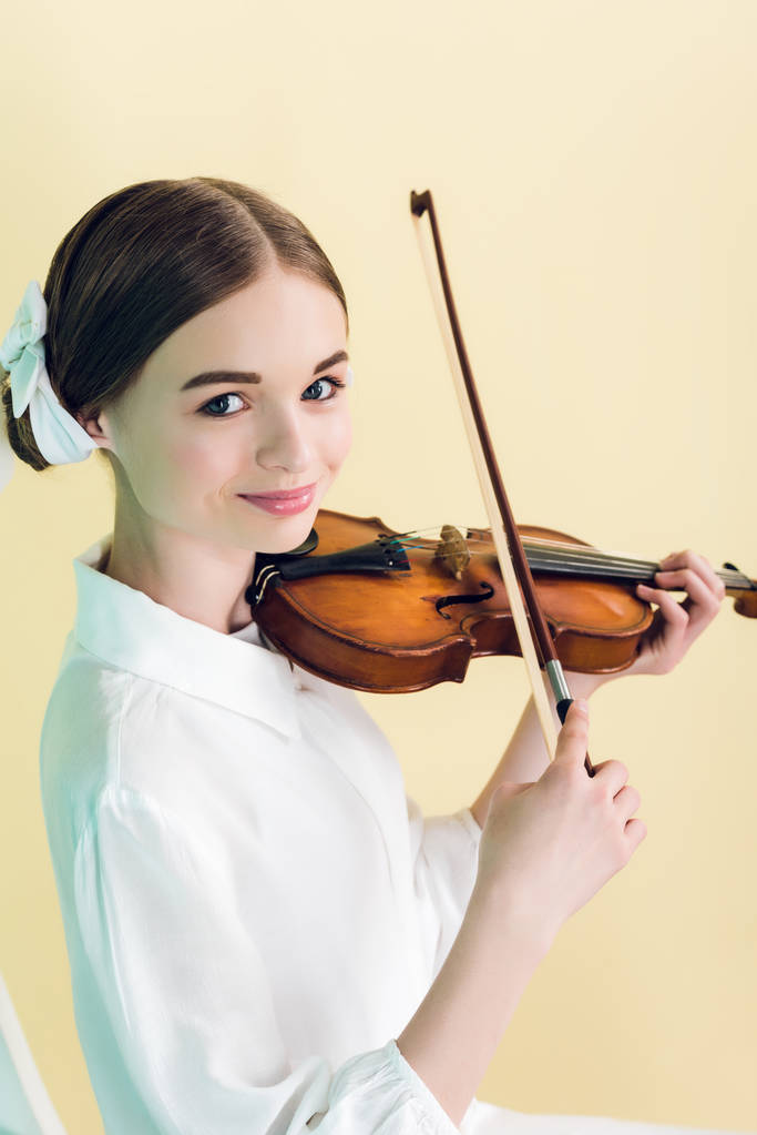 attractive teen girl playing violin, isolated on yellow - Photo, Image