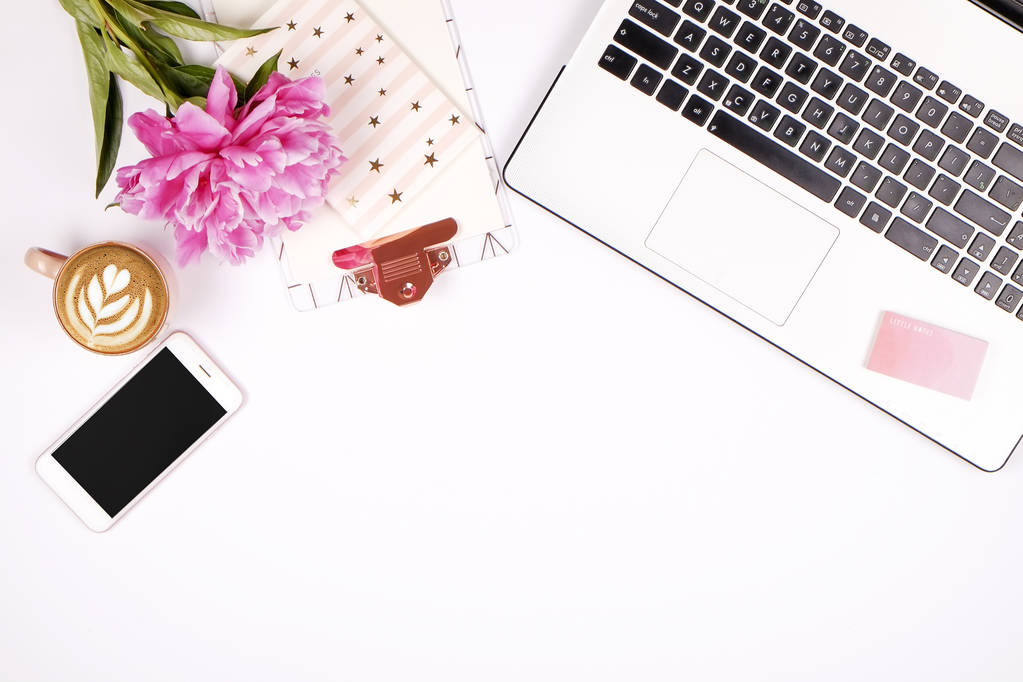 Girly office-bureaublad met zwarte & witte laptop toetsenbord, roze pioen bloemen boeket, kopje koffie, leeg scherm mobiele telefoon, smartphone, pen, levert. Achtergrond plat lag, kopie ruimte, close-up - Foto, afbeelding