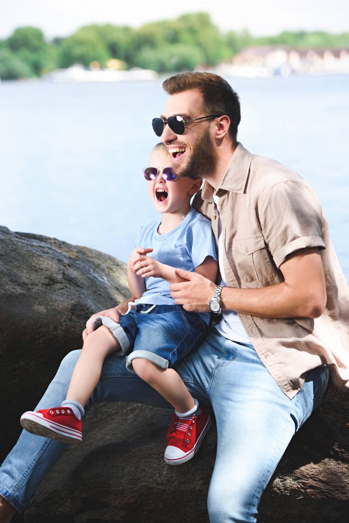 батько і син сміються, дивлячись в парк
 - Фото, зображення