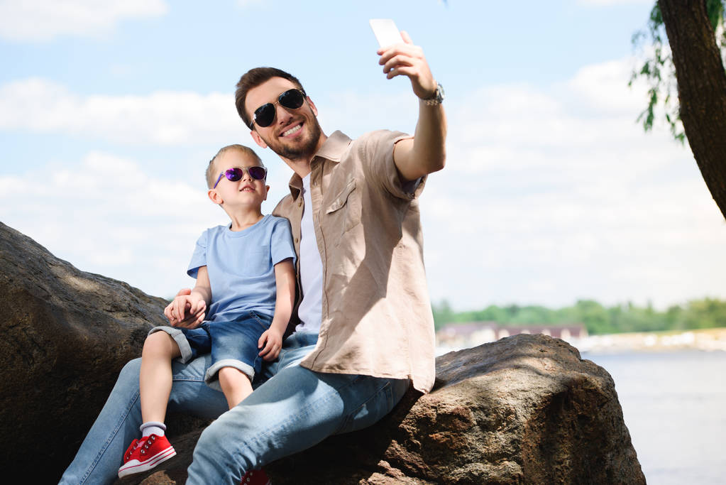 padre e hijo tomando selfie con smartphone en el parque
 - Foto, Imagen