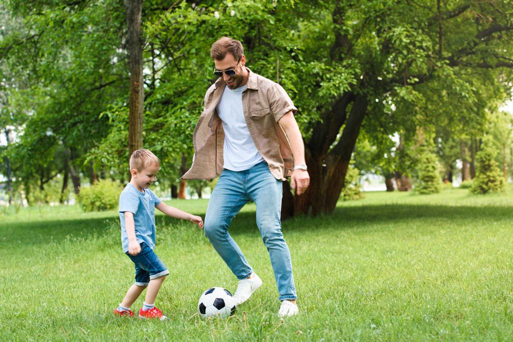 pai e filho se divertindo e jogando futebol no parque
 - Foto, Imagem