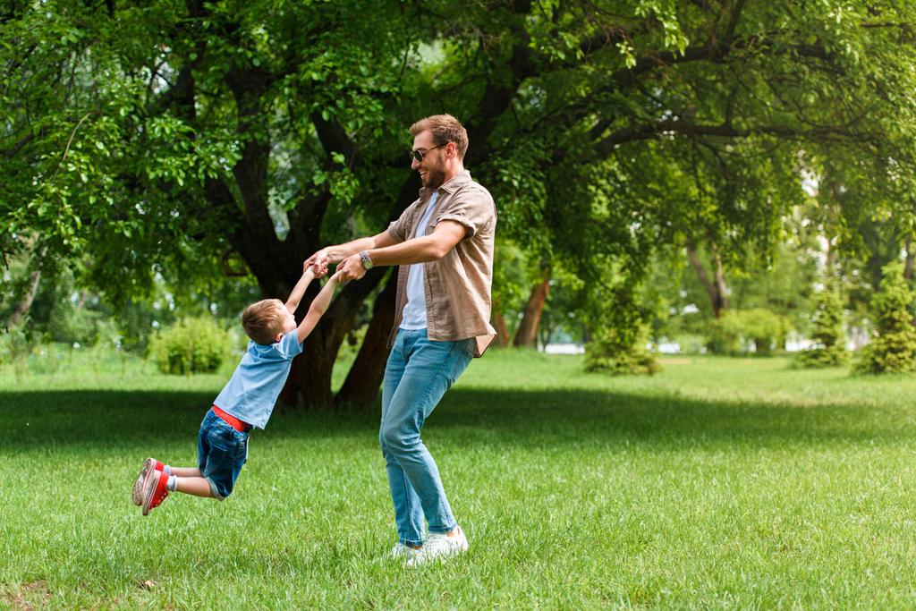 счастливый отец крутится вокруг сына, и они веселятся в парке
 - Фото, изображение