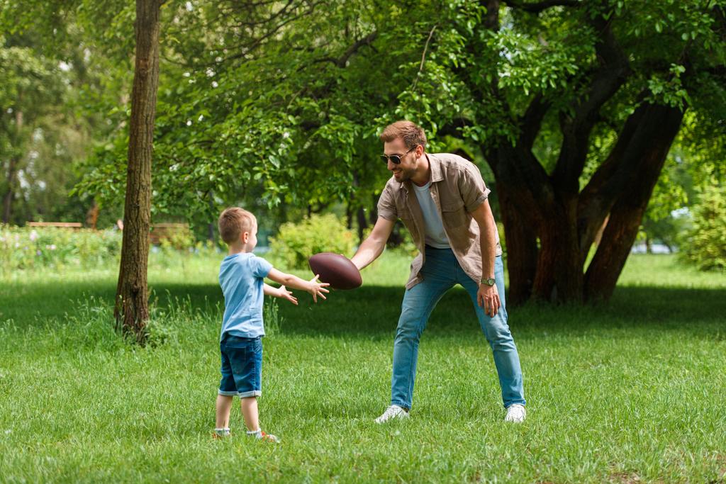 feliz padre e hijo jugando fútbol americano en el parque
 - Foto, Imagen