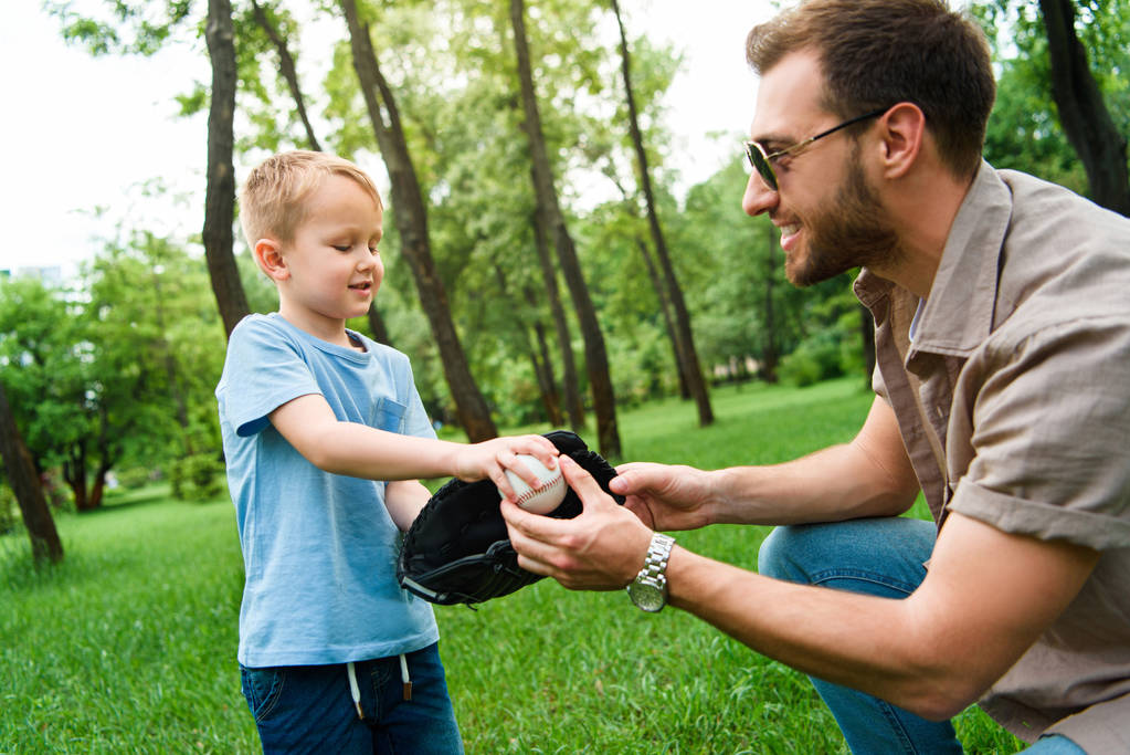 padre dando al figlio palla da baseball e guanto al parco
 - Foto, immagini