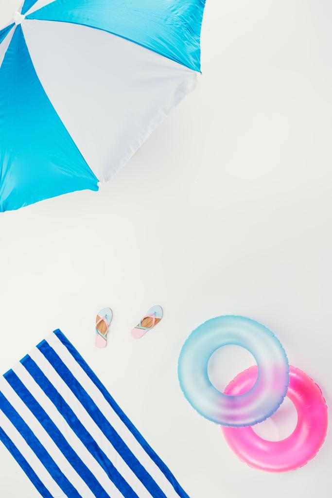 vue du haut du parasol, serviette de plage rayée, tongs et anneaux gonflables isolés sur blanc
 - Photo, image