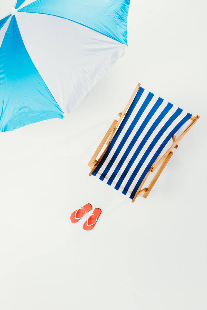 vista superior de sombrilla de playa, silla de playa a rayas y chanclas aisladas en blanco
 - Foto, imagen