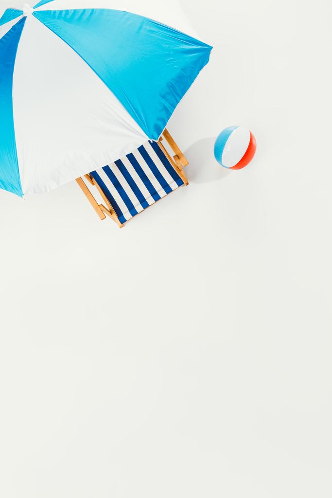 vista superior de la sombrilla de playa, silla de playa a rayas y bola de playa inflable aislada en blanco
 - Foto, Imagen