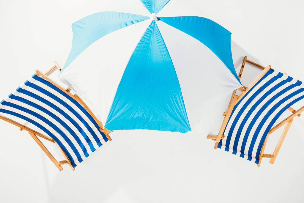 вид сверху на полосатые пляжные стулья и пляжный зонтик, изолированный на белом
 - Фото, изображение