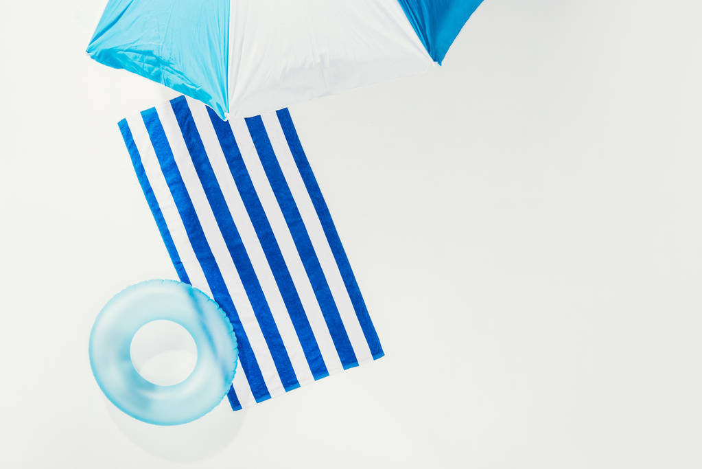vista superior de la sombrilla de playa, toalla rayada y anillo inflable aislado en blanco
 - Foto, imagen