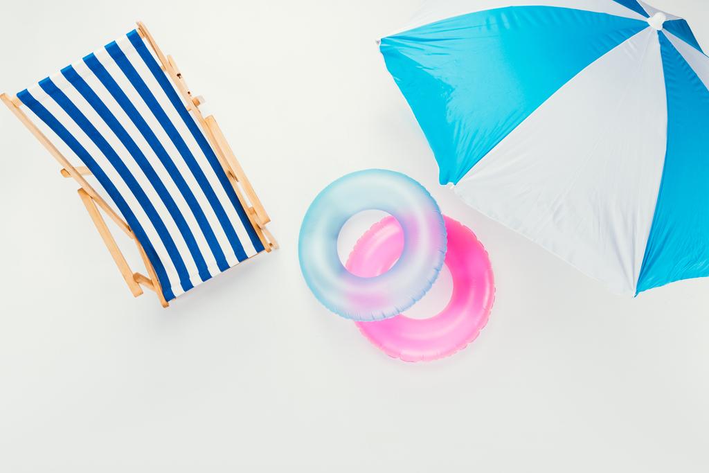 вид зверху на пляжну парасольку, смугасте пляжне крісло і надувні кільця ізольовані на білому
 - Фото, зображення