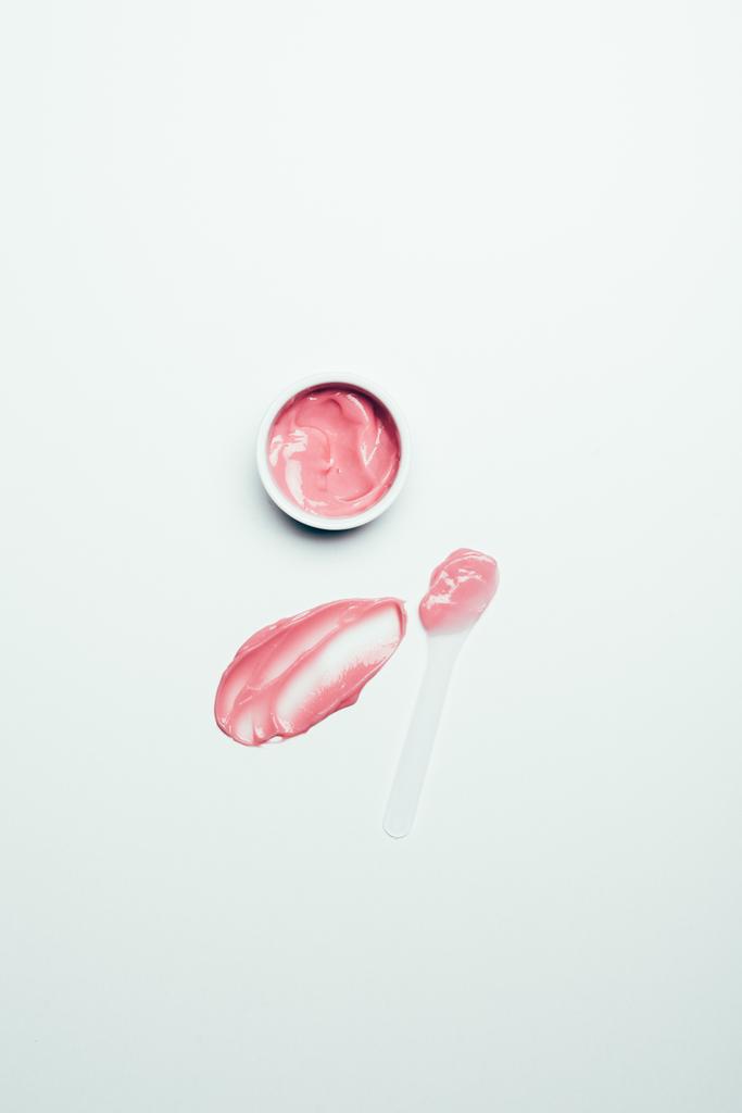 pohled shora rozmazání, lžíce a růžovou masku v kontejneru na bílý povrch - Fotografie, Obrázek