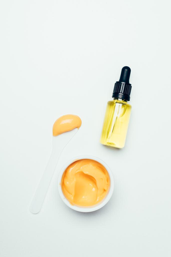 vista dall'alto della bottiglia cosmetica con tubo, cucchiaio e maschera arancione in contenitore isolato su superficie bianca
 - Foto, immagini