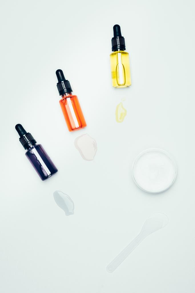 επίπεδη lay με καλλυντικά μπουκάλια με σωλήνες, μουτζούρες, κουτάλι και άργιλος μάσκα σε δοχείο που απομονώνονται σε λευκή επιφάνεια  - Φωτογραφία, εικόνα