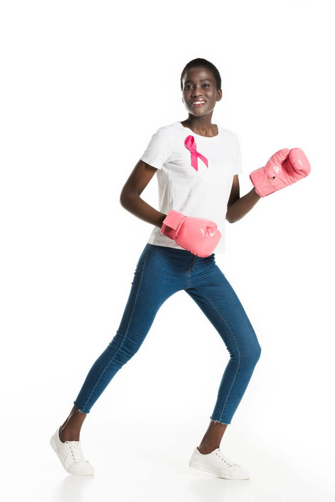 krásná africká americká dívka s růžová stuha boxu a usmívá se na kameru izolované na bílém, pojem rakovina prsu - Fotografie, Obrázek