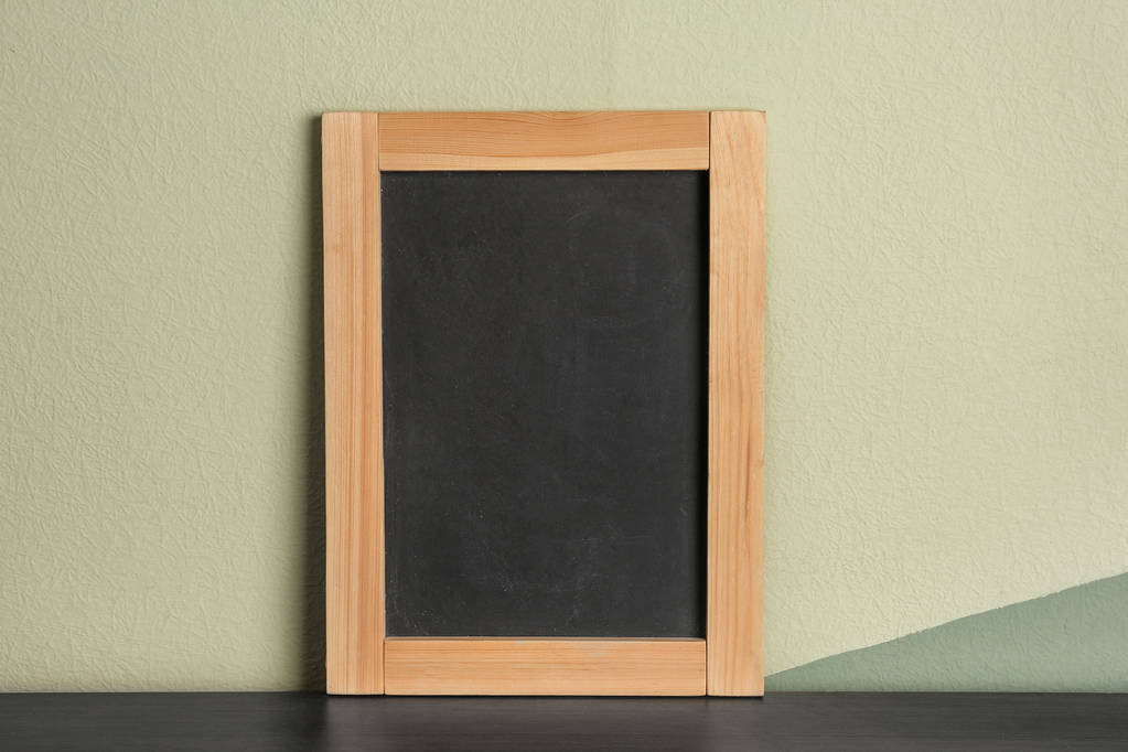 Small clean chalkboard on table near color wall - Photo, Image