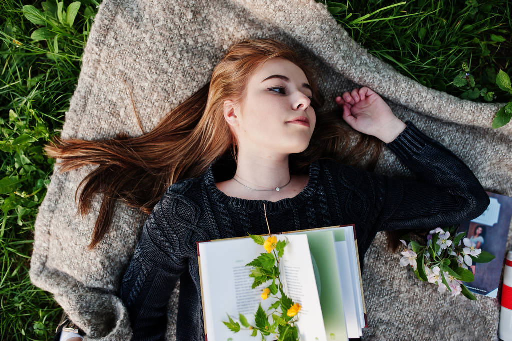 Nuori brunette tyttö makaa ruudullinen kirjan kanssa
. - Valokuva, kuva