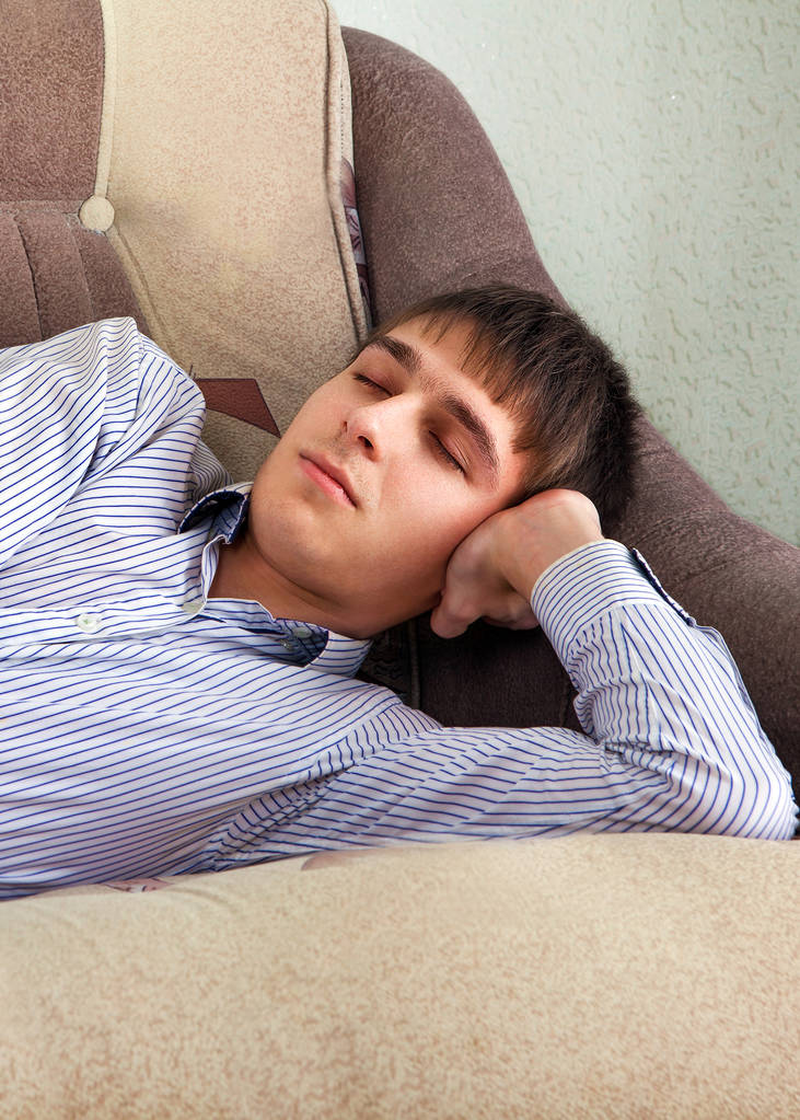 Väsynyt nuori mies nukkuu sohvalla kotona - Valokuva, kuva