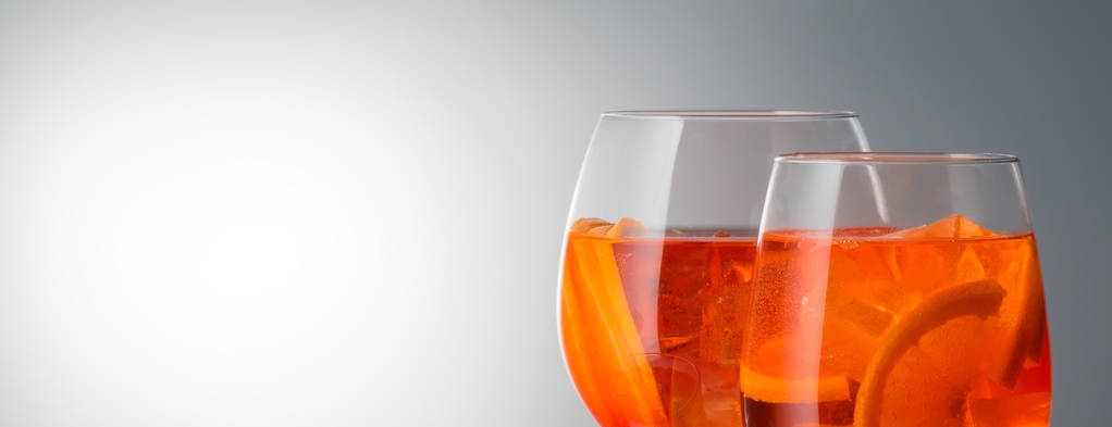 Trendy populaire boisson italienne été rafraîchissant cocktail légèrement alcoolisé Aperol spritz dans un verre avec de la glace décorée avec des tranches d'orange sur fond dégradé gris blanc diffusion de la lumière Publicité promotionnelle shot set de trois verres différents
 - Photo, image