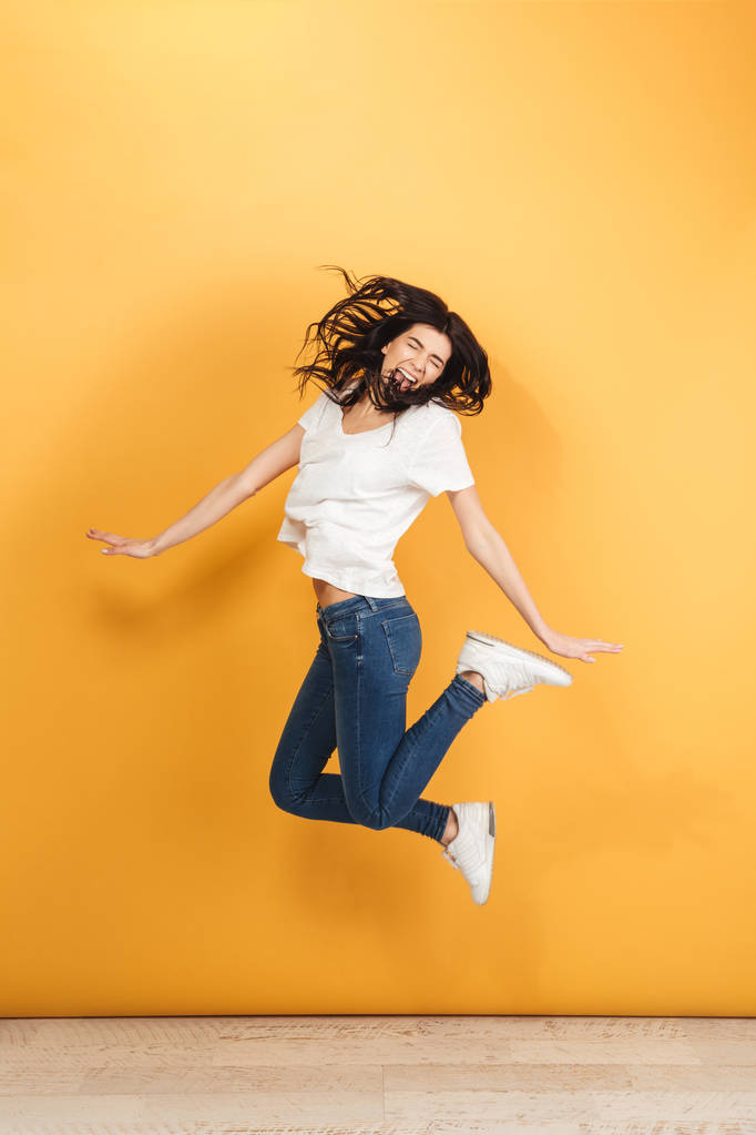 Kuva nuori huutaa emotionaalinen nainen hyppää eristetty yli keltainen tausta
. - Valokuva, kuva