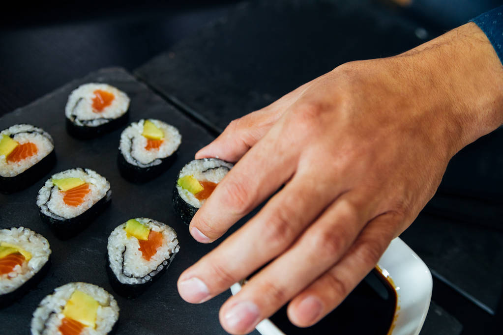 Sushi su un piatto raccolto da un uomo
 - Foto, immagini