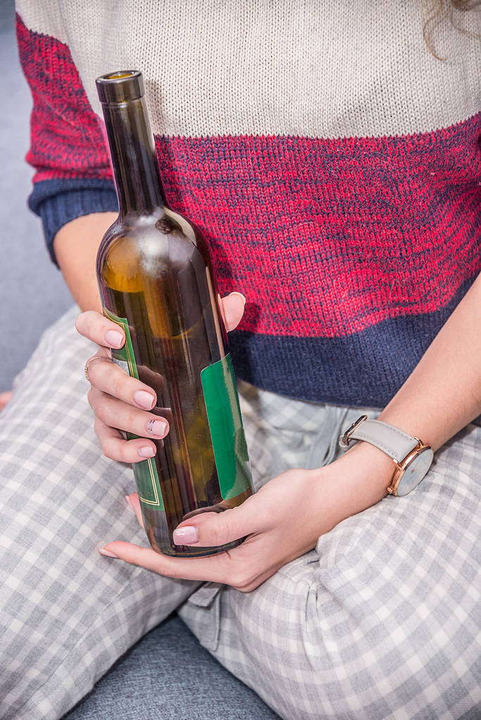 meisje met een fles wijn in de hand, het drinken van alcohol, hoofdpijn met een kater - Foto, afbeelding