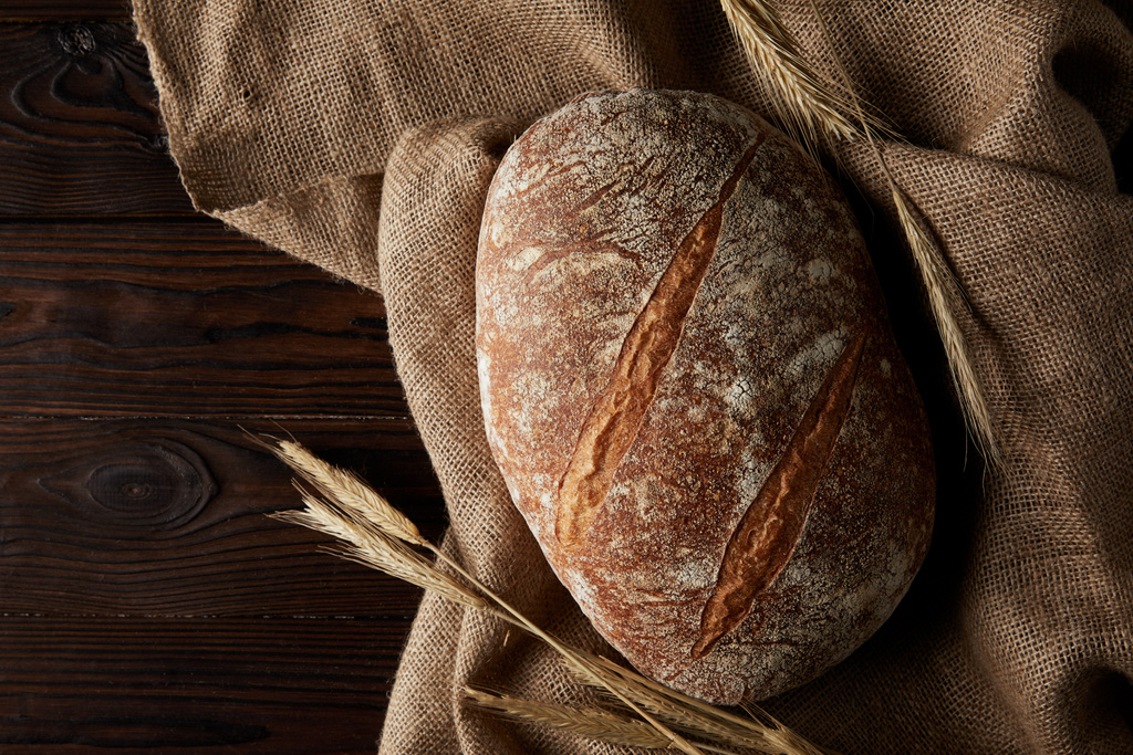 pohled shora chléb, pšenice a žíně na rustikální dřevěný stůl  - Fotografie, Obrázek
