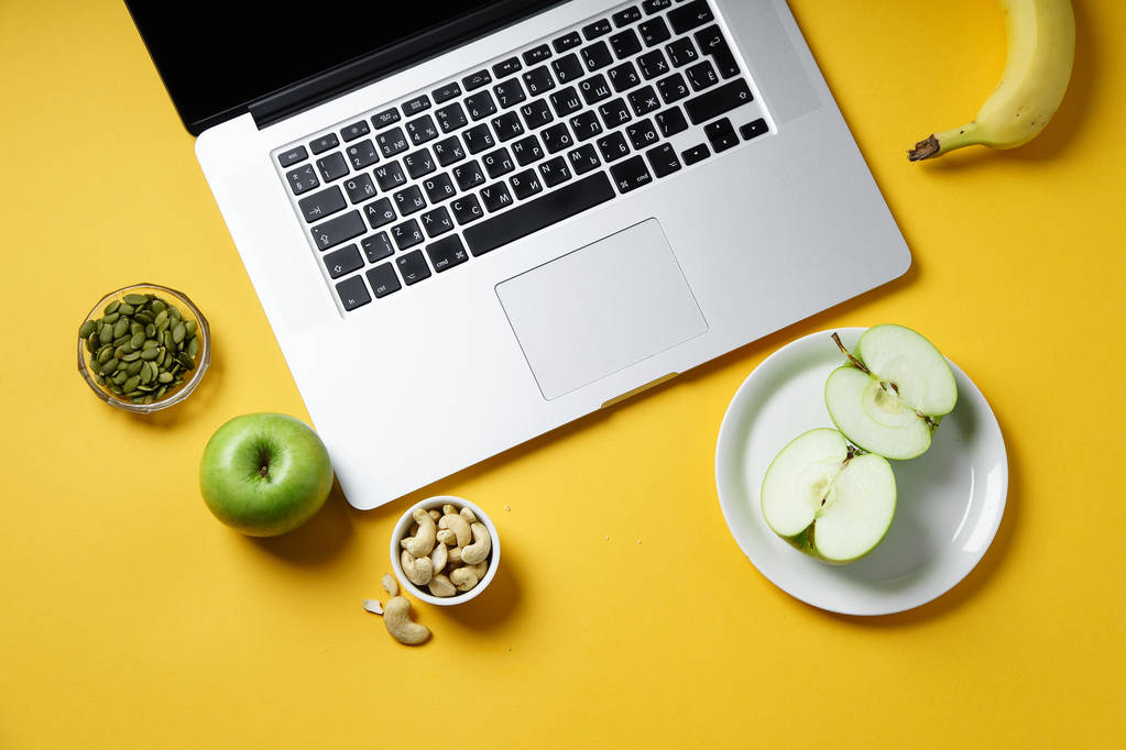 Laptop und gesunde Snacks auf gelbem Hintergrund, modernes Lifestylekonzept  - Foto, Bild