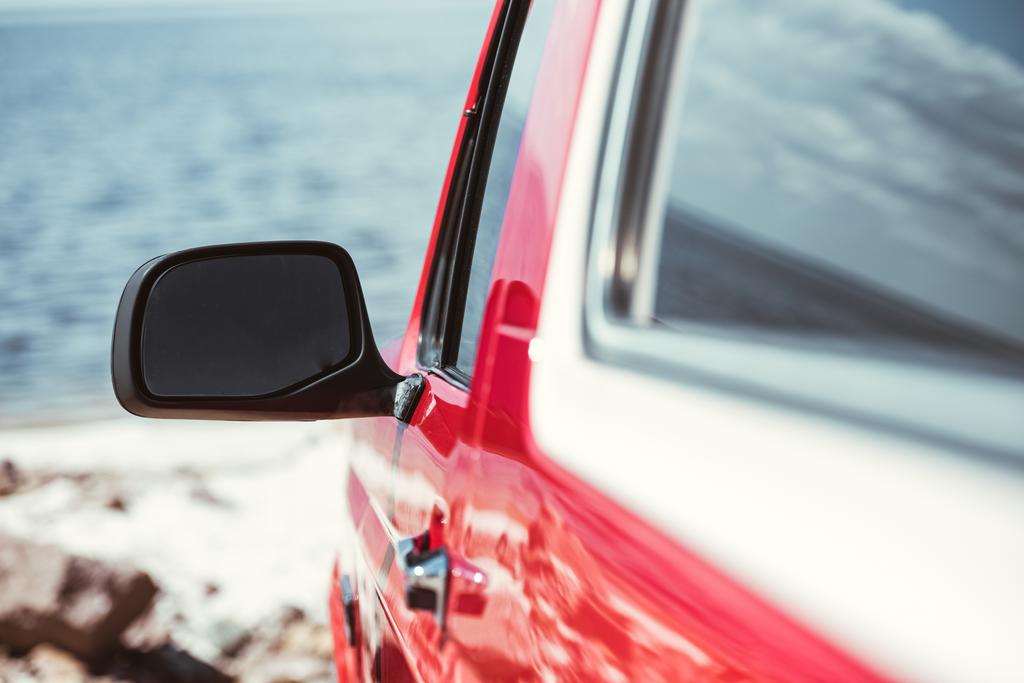 selective focus of car mirror, red jeep near the sea - Photo, Image