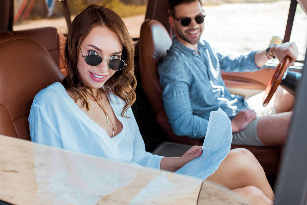beautiful couple of travelers looking at map in car during road trip - Photo, Image