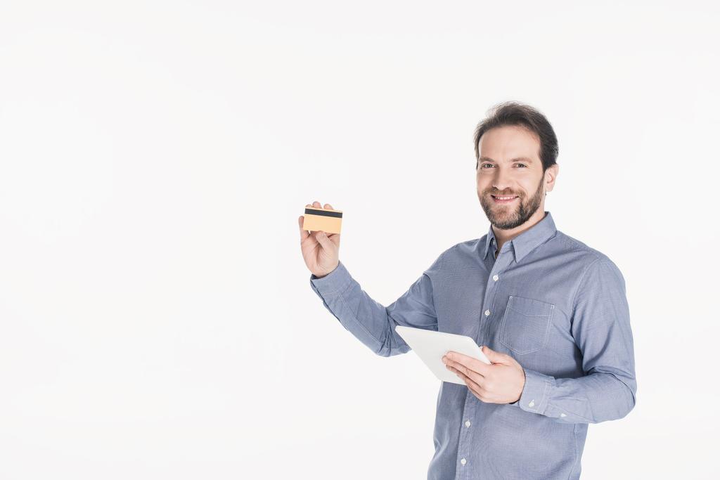 Porträt eines lächelnden Mannes mit digitalem Tablet, das Kreditkarte isoliert auf Weiß zeigt - Foto, Bild