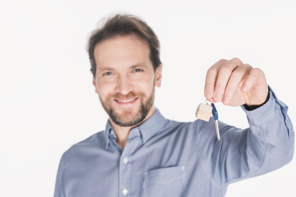 Yeni evinden anahtarı elinde gösterilen gülümseyen adam portresi üzerine beyaz izole - Fotoğraf, Görsel
