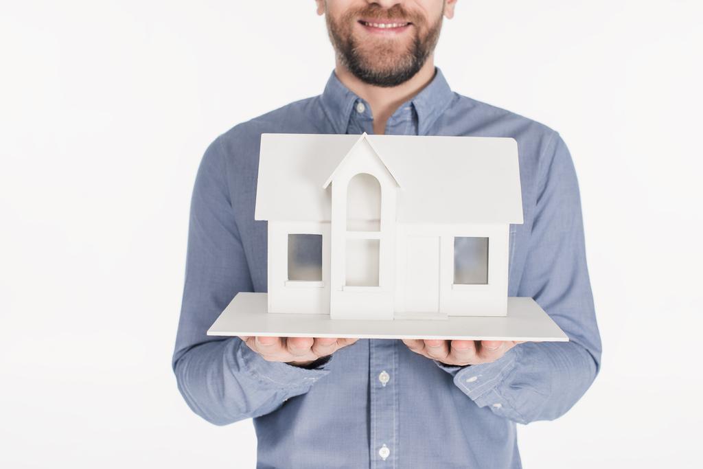 обрізаний знімок бородатого чоловіка, що тримає модель будинку в руках ізольовано на білому
 - Фото, зображення