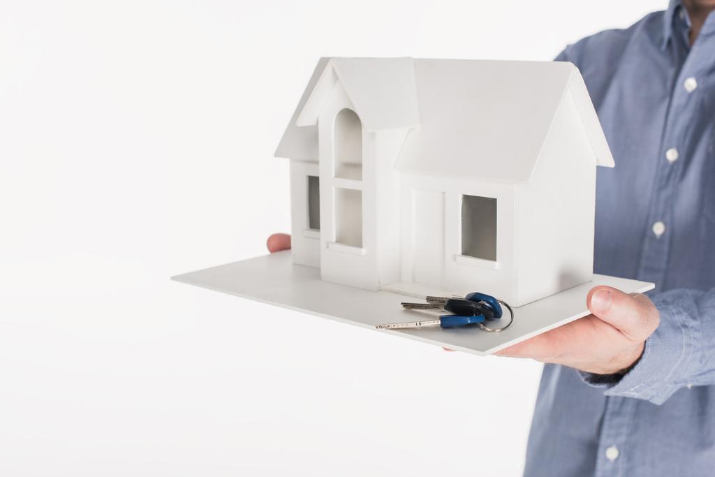 részleges kilátás nyílik ember tartja a ház modell és kulcsok kezében elszigetelt fehér - Fotó, kép