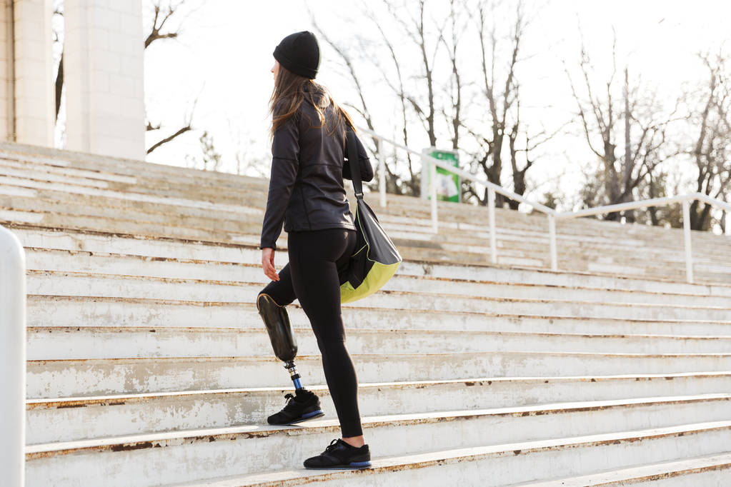 Vissza a meghibásodott fut a lány protetikai lábát a Sportruházat gyaloglás fel a lépcsőn kívül fitness stadion fotó - Fotó, kép