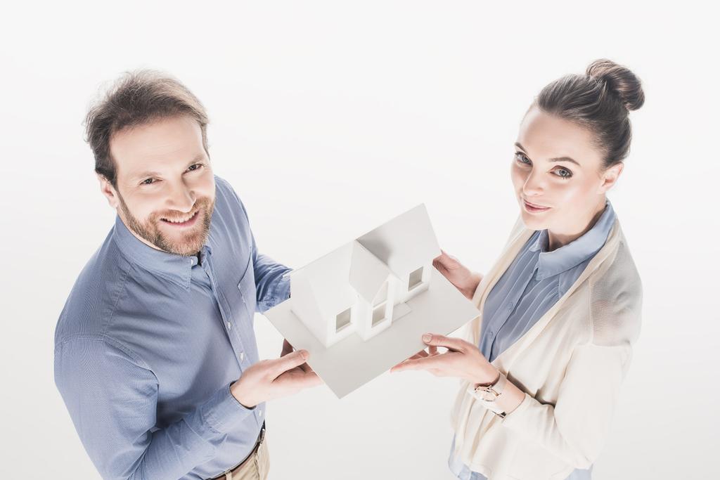 hoge hoekmening van echtpaar huis model bij elkaar te houden geïsoleerd op wit - Foto, afbeelding