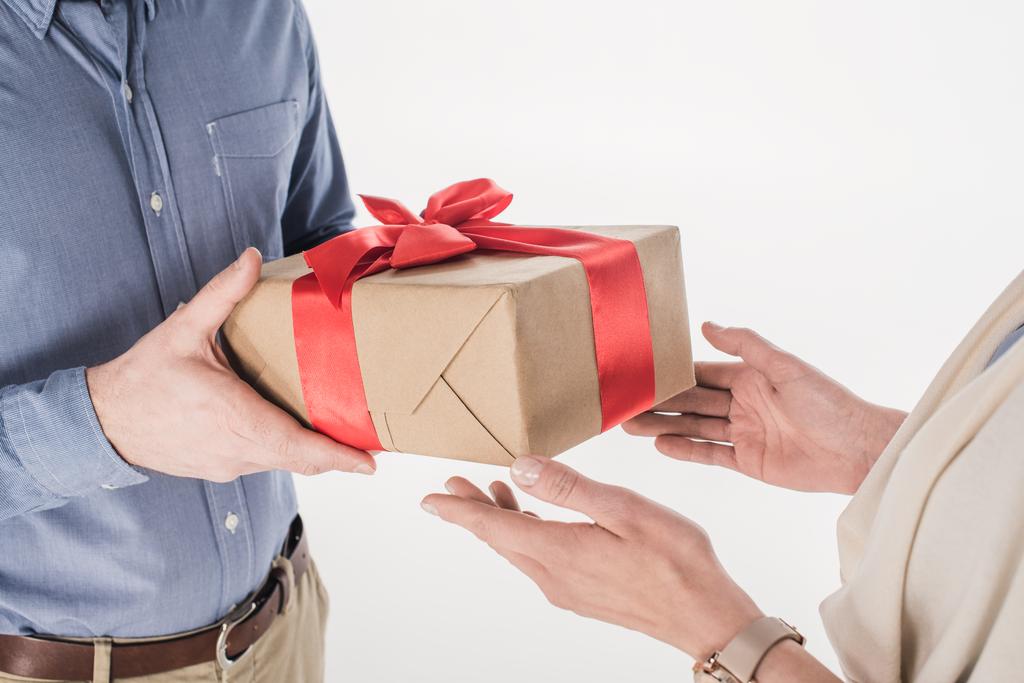 Seitenansicht des Mannes präsentiert verpacktes Geschenk an Frau isoliert auf Weiß - Foto, Bild