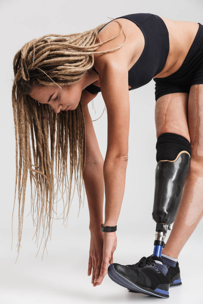Εικόνα του μια καταπληκτική υγιή νεαρό αθλήτρια με αναπηρία, απομονώνονται σε γκρι φόντο. Ψάχνετε παρεμπιπτόντως κάνουν ασκήσεις. - Φωτογραφία, εικόνα