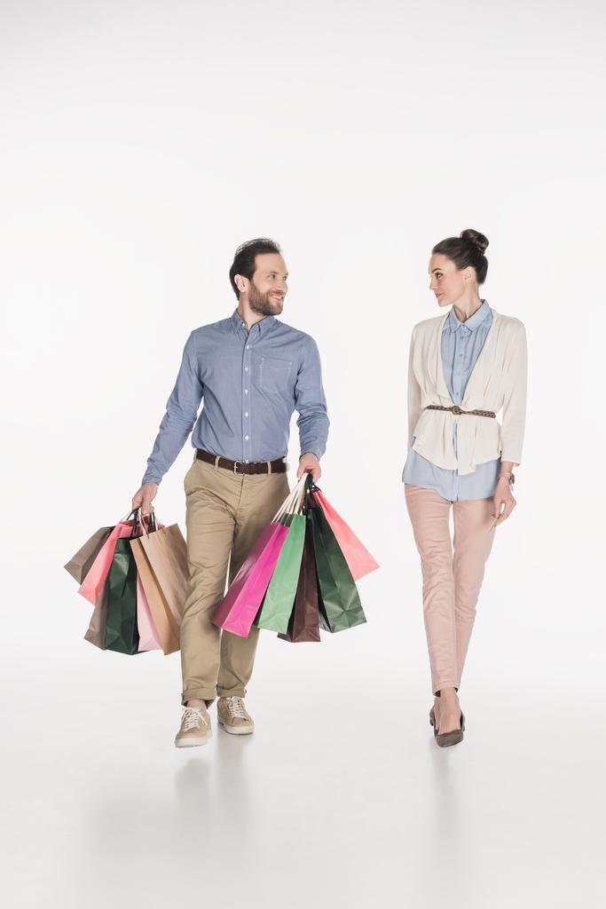 Žena při pohledu na usmívající se manžel, nošení nákupní tašky izolované na bílém - Fotografie, Obrázek