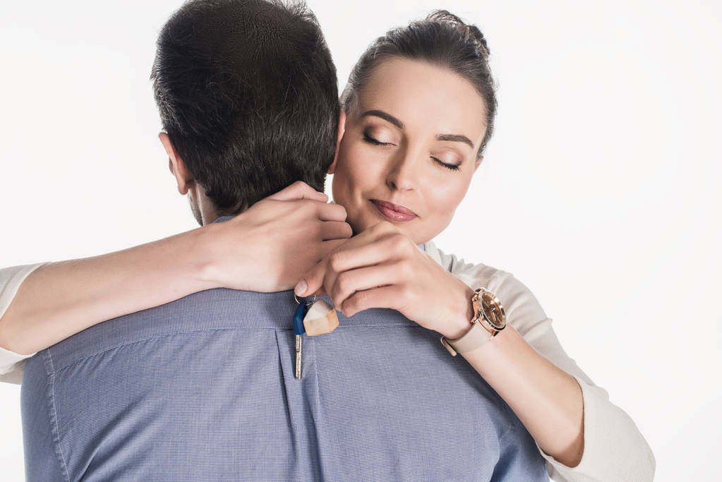 gedeeltelijke weergave van vrouw met sleutel van nieuwe huis knuffelen echtgenoot geïsoleerd op wit - Foto, afbeelding