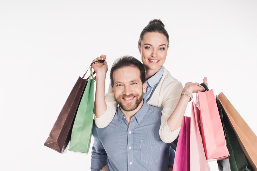 Szczęśliwa kobieta z torby na zakupy a mąż piggybacking razem na białym tle - Zdjęcie, obraz