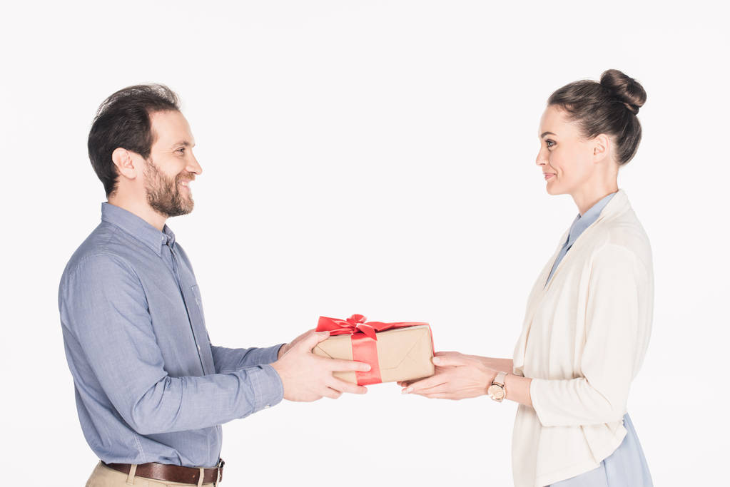 widok boczny uśmiechnięty mężczyzna przedstawiając owinięty prezent dla żony na białym tle - Zdjęcie, obraz