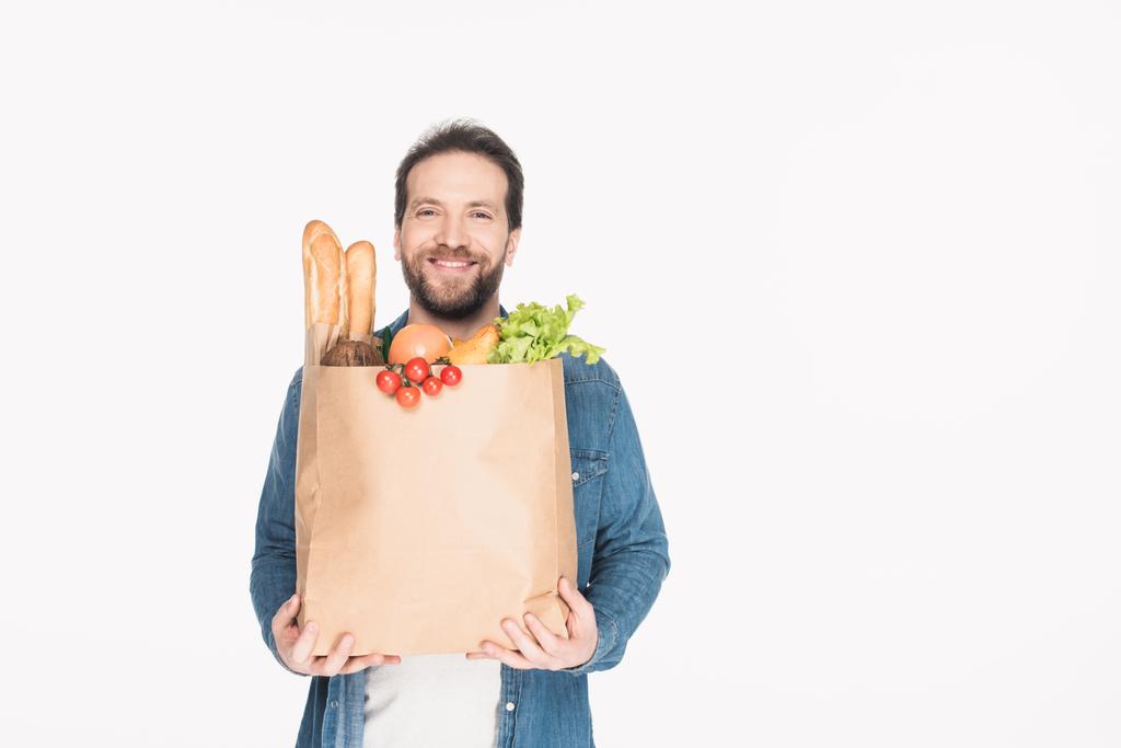 Porträt eines lächelnden bärtigen Mannes mit Papierverpackung mit Lebensmittelgeschäft isoliert auf weiß - Foto, Bild