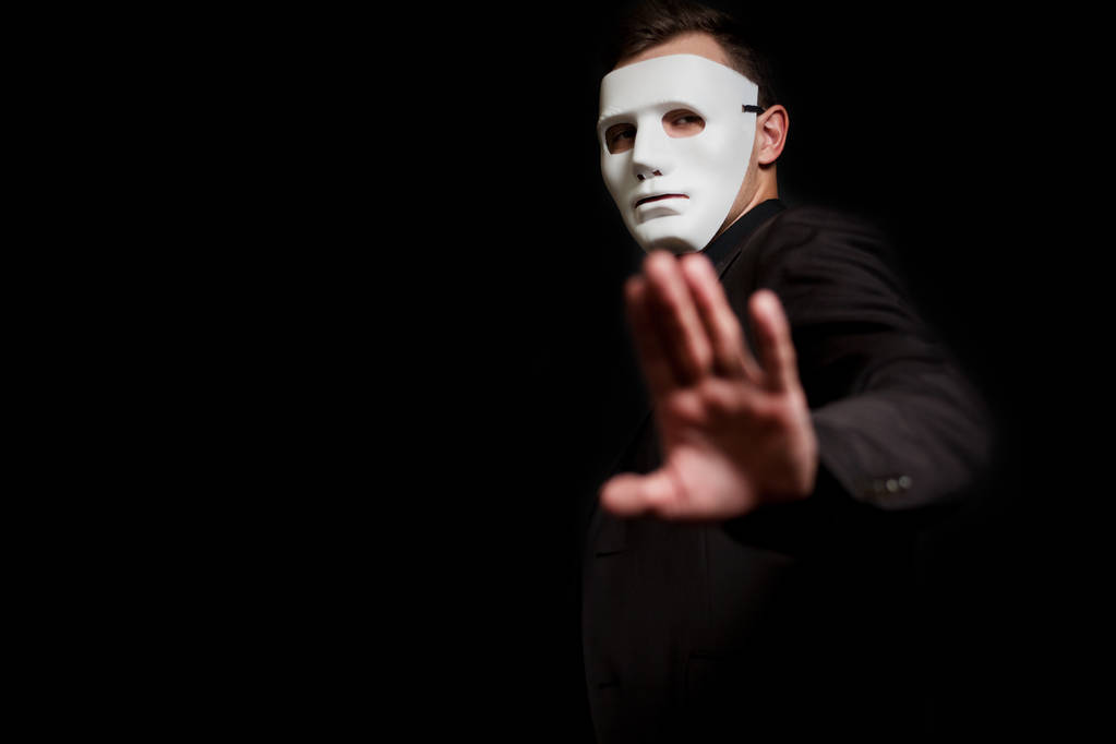 Man in een wit masker op een zwarte achtergrond - Foto, afbeelding