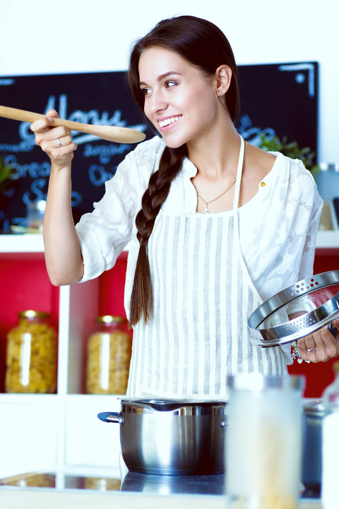 Kookvrouw in keuken met houten lepel. Kokende vrouw - Foto, afbeelding