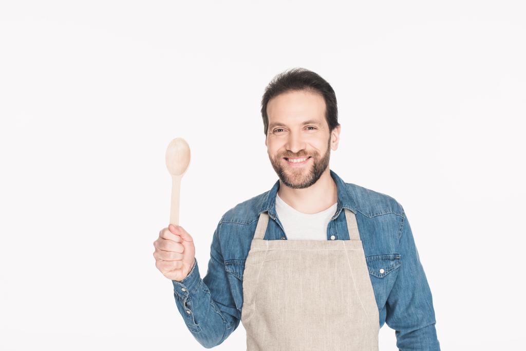 portrait of smiling man in apron with wooden spoon isolated on white - Photo, Image