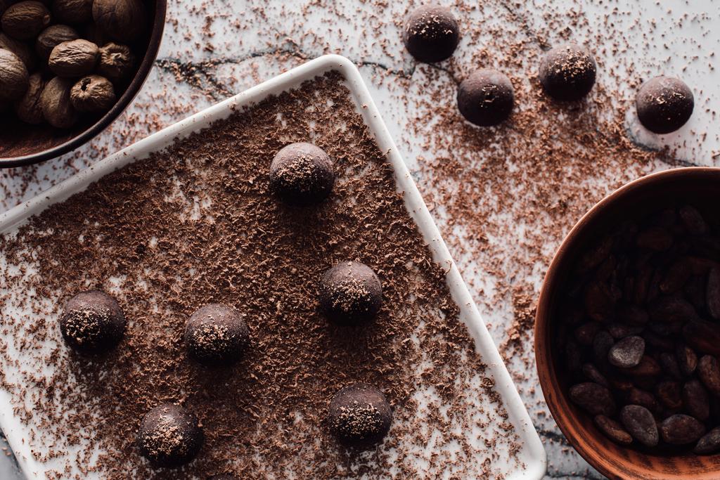 Widok z góry z miski z nutmegs i kakao, płyta z truflami, obejmujące przez wiórkami czekolady na marmurowym stoliku  - Zdjęcie, obraz
