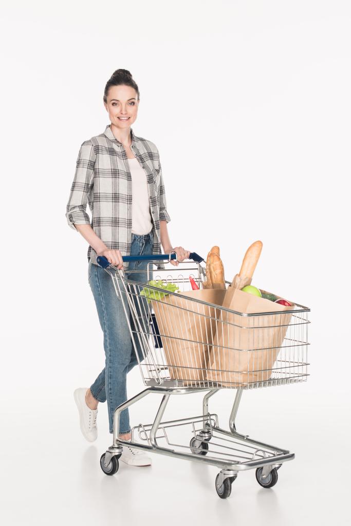 vrolijke vrouw met papier pakketten in winkelwagen geïsoleerd op wit - Foto, afbeelding