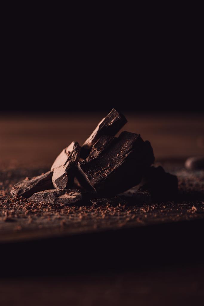 Close-up shot van geraspte pure chocolade en stukjes chocolade op houten tafel - Foto, afbeelding