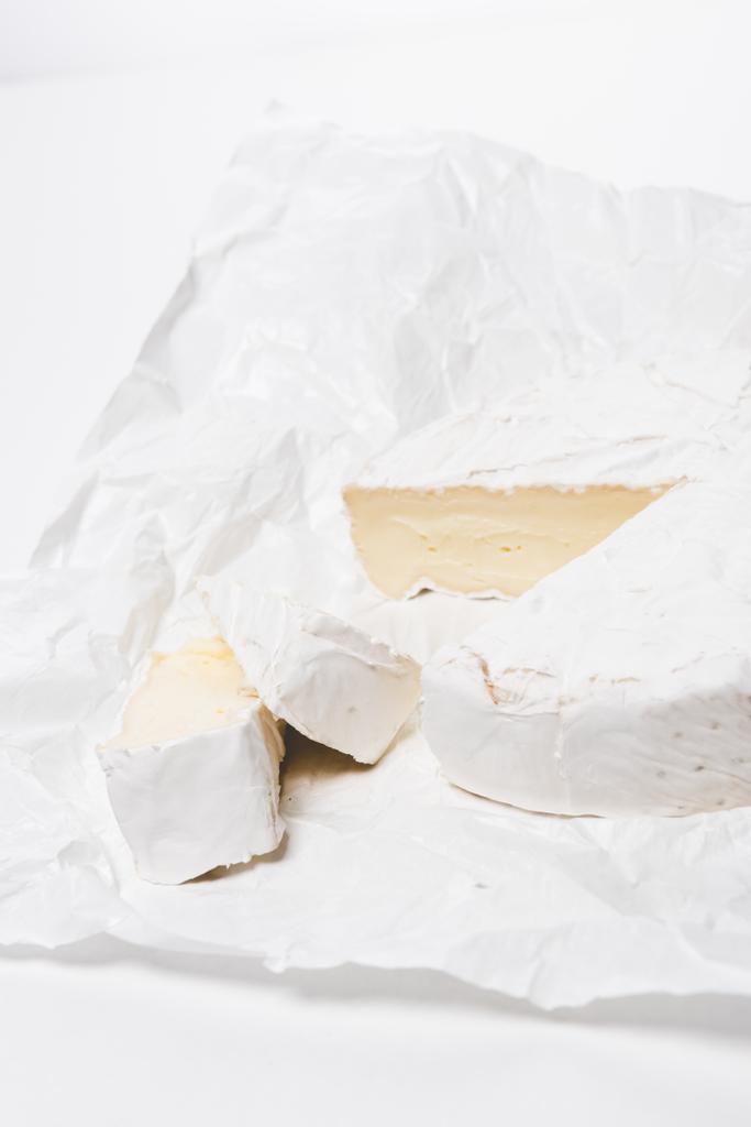 primo piano di formaggio brie affettato su carta sgualcita e su superficie bianca
 - Foto, immagini